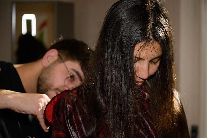 Eine Person schneidet einer anderen Person die Haare.
