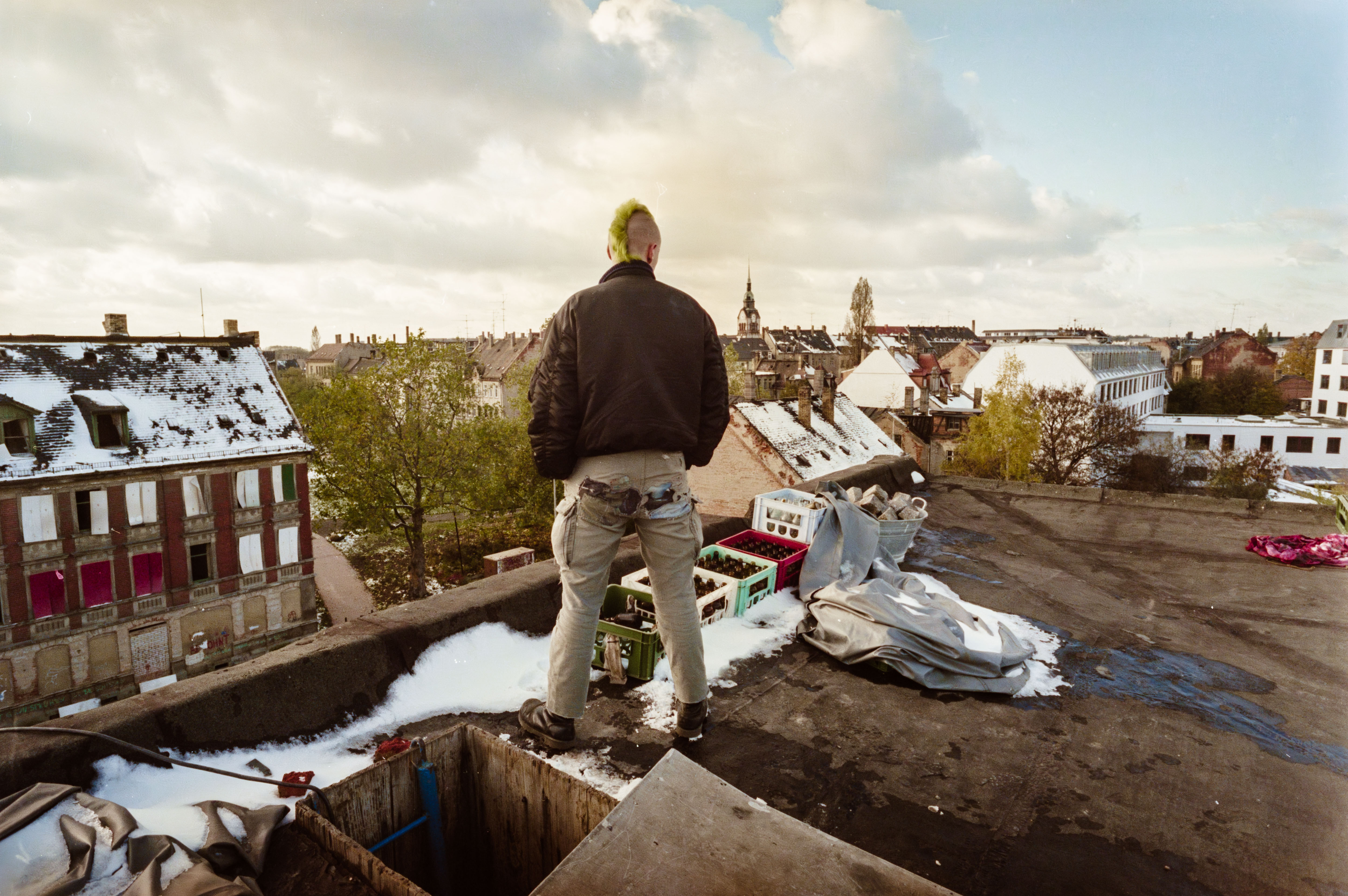 Punk steht mit Glasflaschen auf einem Flachdach